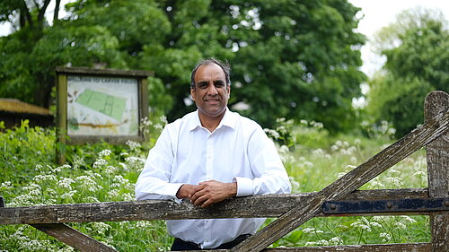 Cllr Shaffaq Mohammed in front of a field with flowers in