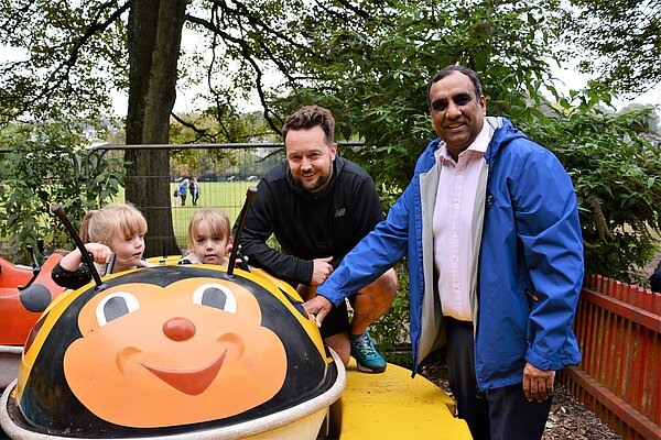 Shaffaq Mohammed in a park alongside two smiling children and their dad.