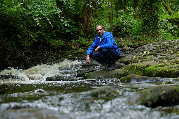 Shaffaq Mohammed knelt next to a river